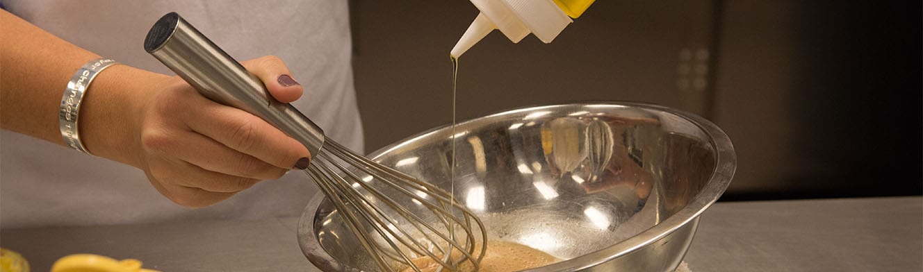 A student is whisking vegetable oil in a bowl