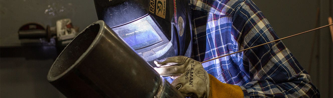 A student welds a large pipe