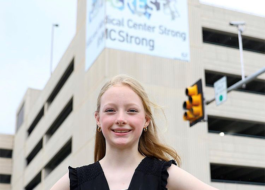 Hannah Brown stands in front of Hillcrest Medical Center with her winning mural.