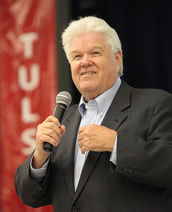 John Hunter holding a microphone while speaking at an event