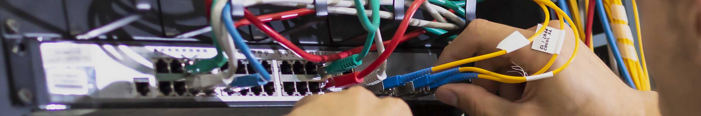 A student works with patch cable on a rack of equipment