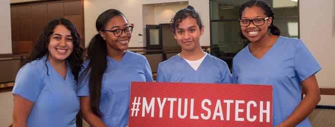 Four students hold a #MyTulsaTech sign on the first day of school at the Health Sciences Center.