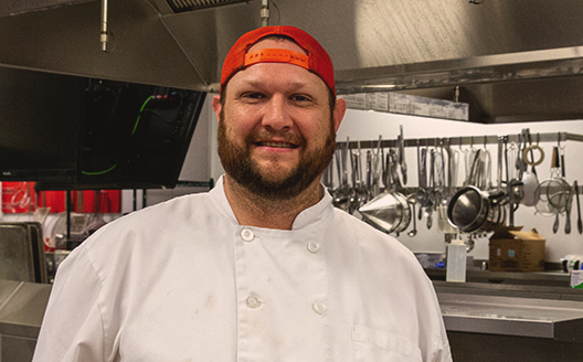Brian Kiss smiles for photo in his culinary uniform