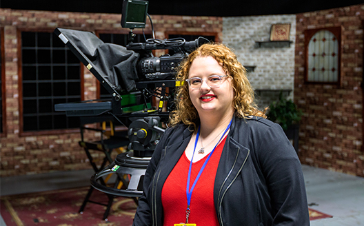 Adult TV Production student Brooc Simpson stands in front of a TV camera