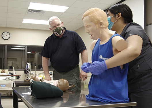Health Science student performs the Heimlich maneuver on a manikin.