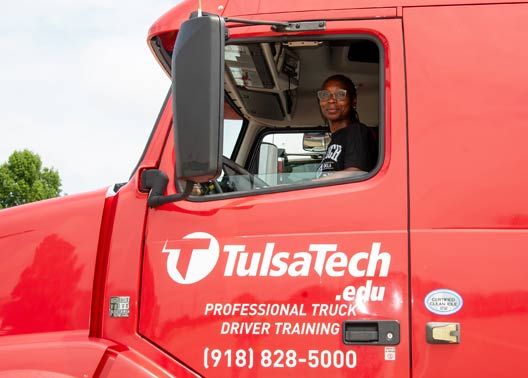Student Precious Cannon looks out the driver's side window of a red, Tulsa Tech truck